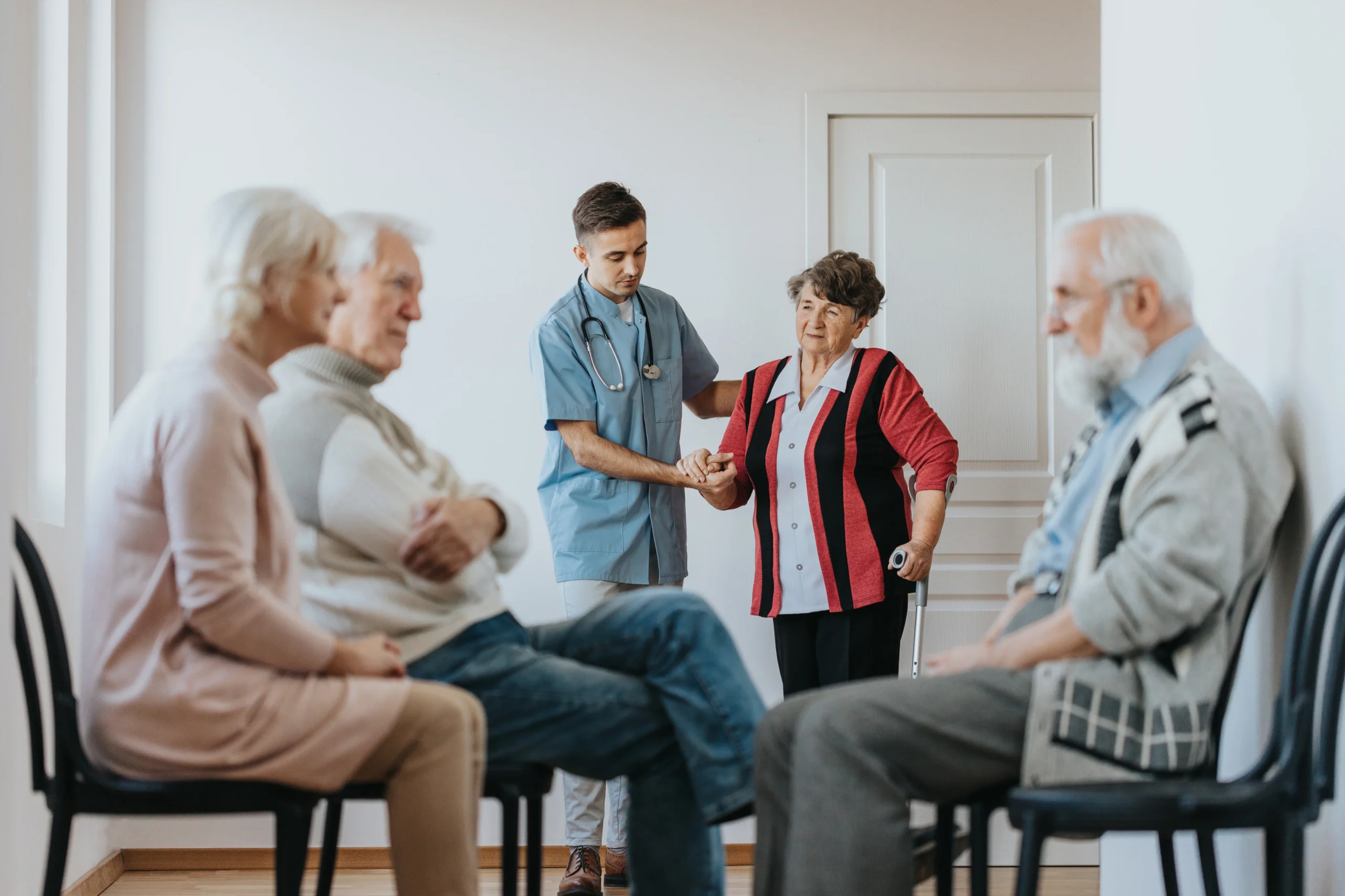 Young doctor helping to an older patient walking out of the office